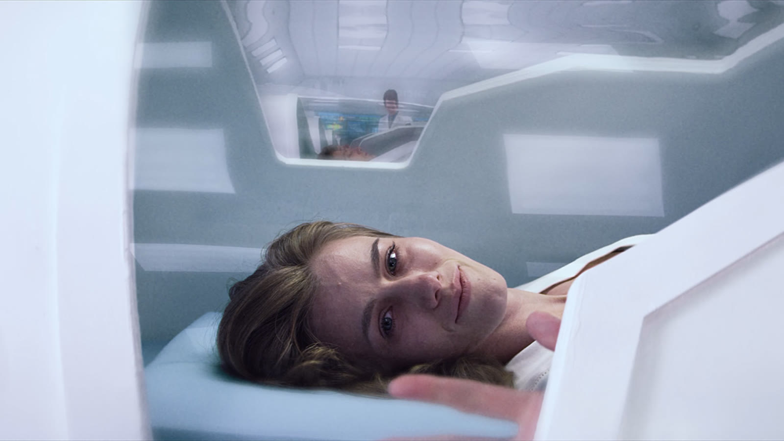 A woman lying inside a white medical hibernation pod.